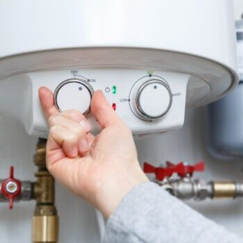 Female hand turning on electric water heater (boiler).