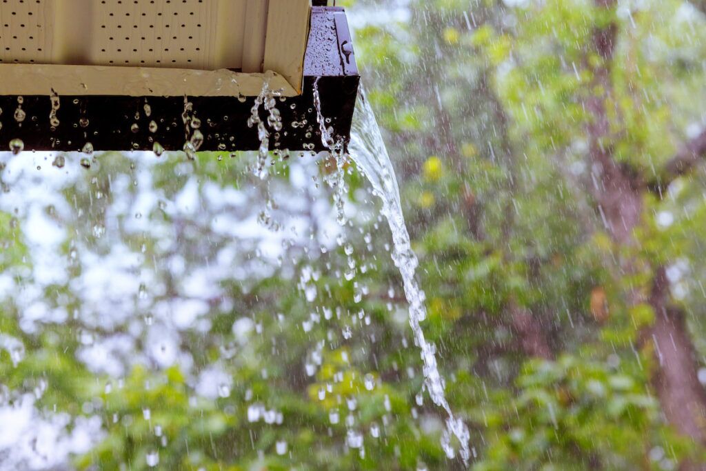 During heavy rain, water cascades from the overflowing gutters.